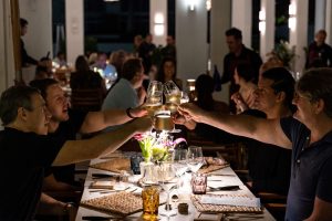 Friends celebrate with champagne glasses at a festive dinner table, surrounded by a vibrant atmosphere and soft lighting.