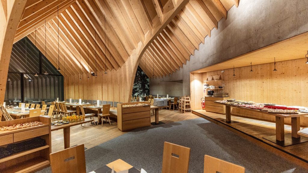 Rustic restaurant interior featuring wooden beams, a buffet table with gourmet dishes, and elegant seating arrangements.