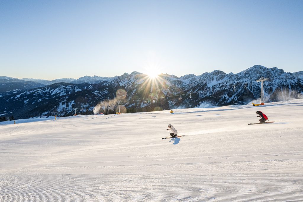 Skiers navigate fresh powder on a sunny day in the Dolomites, surrounded by magnificent mountain scenery.