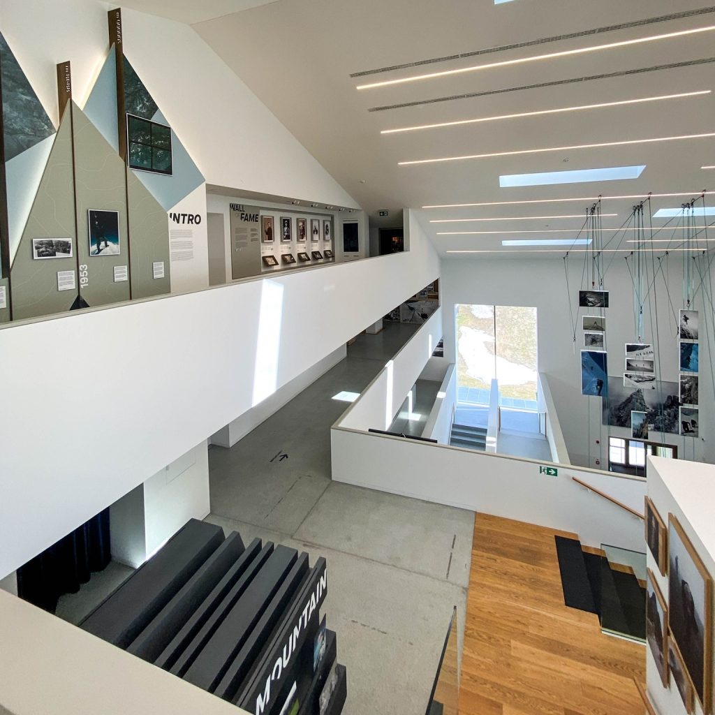 Interior view of a modern alpine center showcasing ski history and exhibits with large windows and bright lighting.