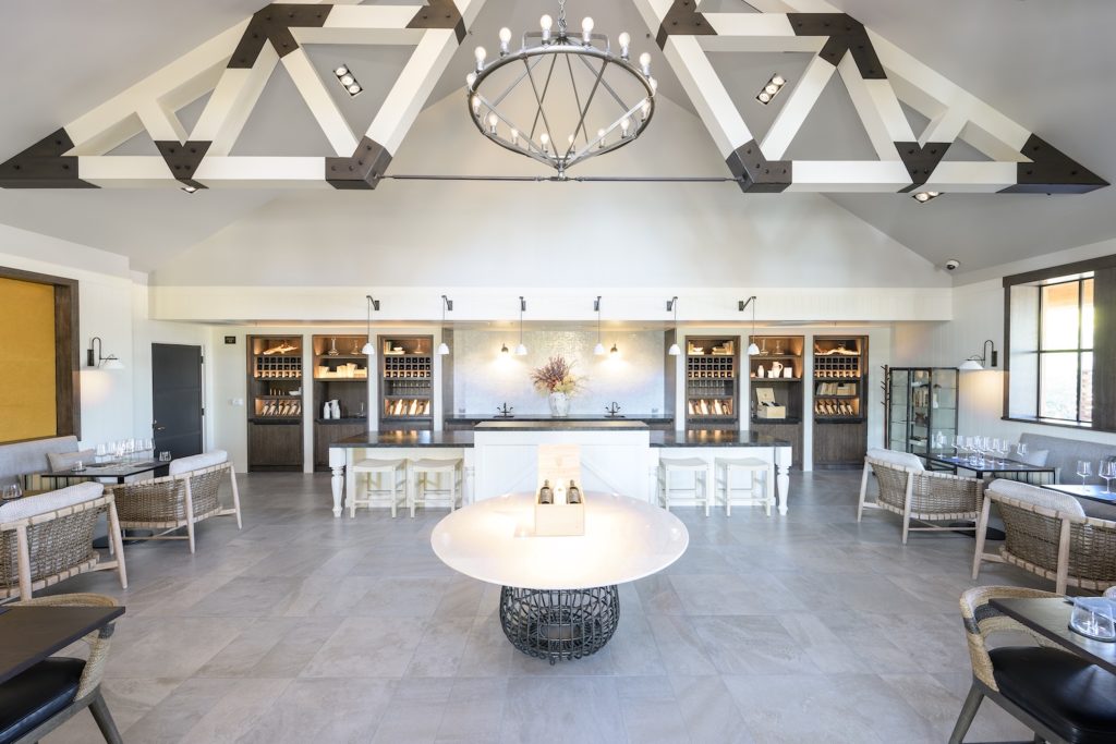Bright, modern tasting room at Elusa Winery featuring minimalist decor, a large chandelier, and inviting seating areas.