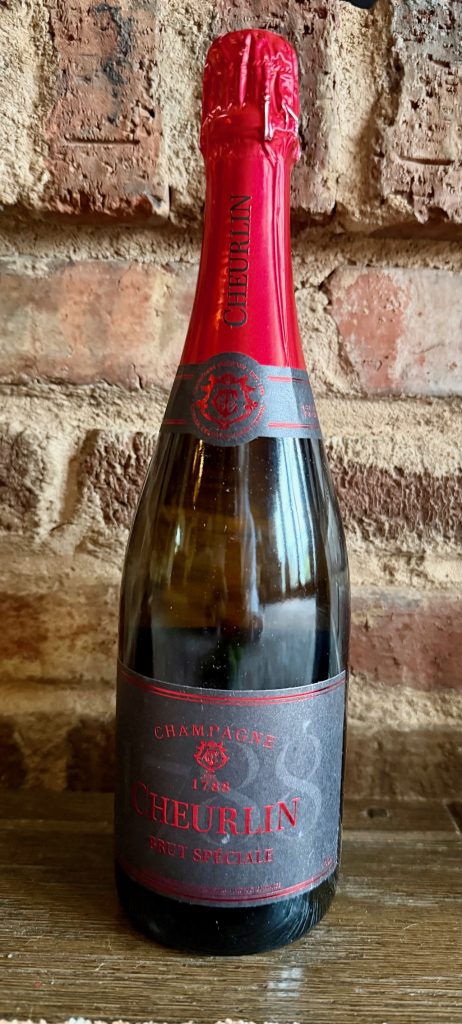 Luxury kosher champagne bottle labeled Cheurlin Brut Spéciale against a brick background.