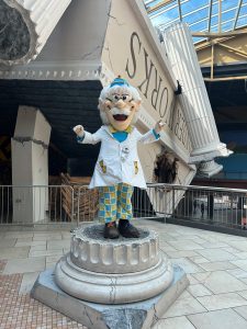 A character in a lab coat stands on a pedestal, surrounded by a playful science-themed environment at WonderWorks Destiny.