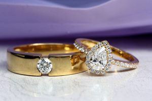 Gold engagement rings featuring a round diamond band and a pear-shaped diamond ring with smaller gems.