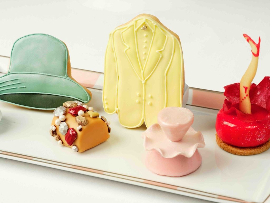 Colorful cookies shaped like hats and formal wear, displayed on a plate as part of the Red Carpet Style Afternoon Tea.