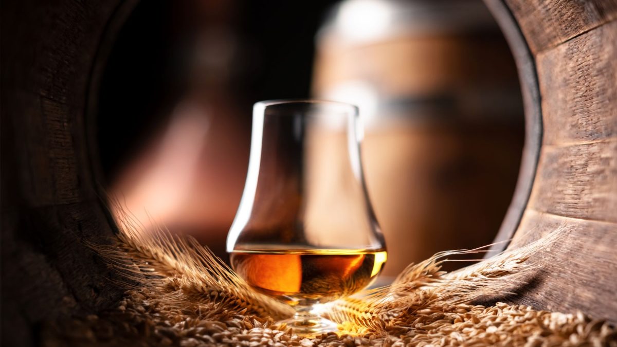 A whiskey glass sits on a bed of grains, highlighting the allure of military whiskey for collectors and enthusiasts.