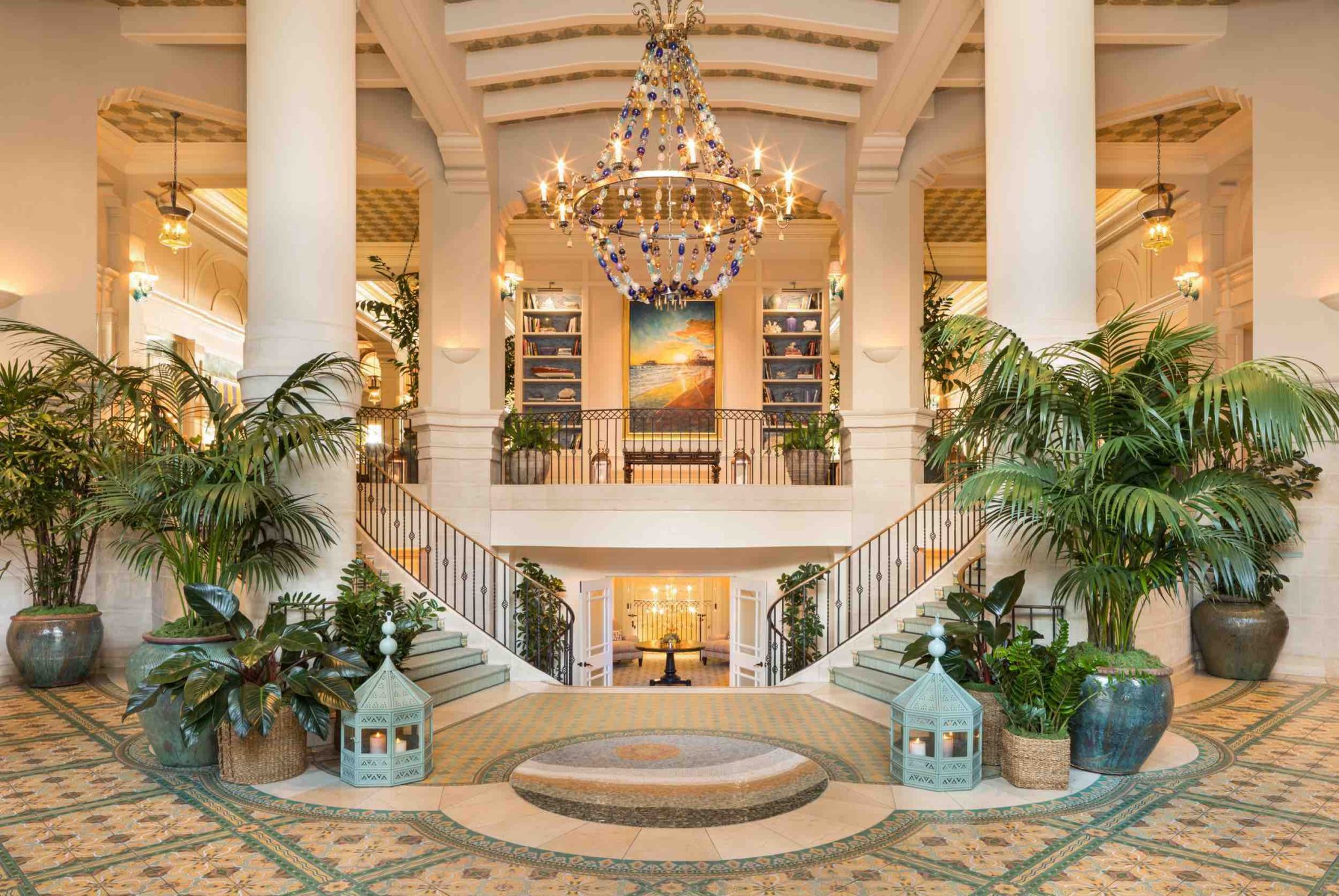 Luxurious lobby of Hotel Casa del Mar features a grand chandelier, vibrant plants, and elegant staircase in a coastal setting.