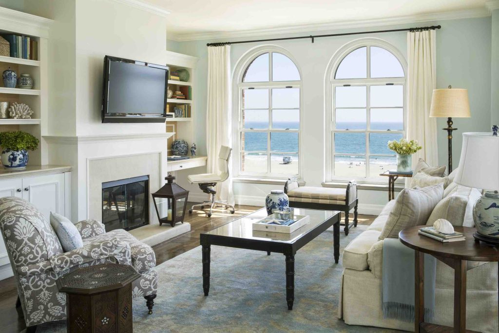 Cozy hotel room with beach views, featuring a stylish design, comfortable seating, and a modern entertainment setup.