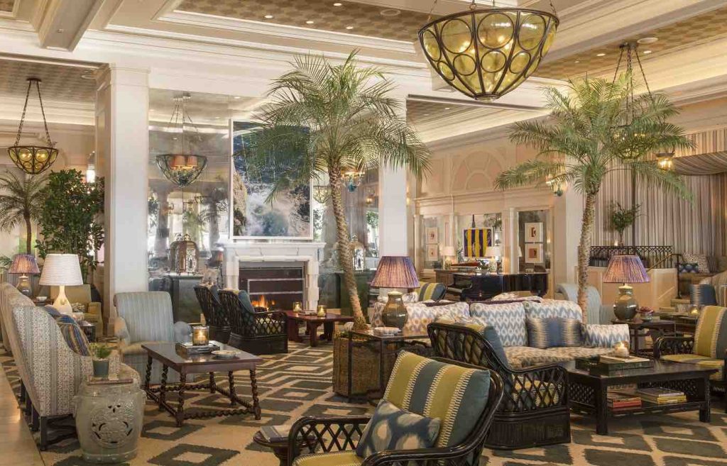Luxurious lobby of Hotel Casa del Mar featuring elegant seating, palm trees, and warm lighting, creating a welcoming atmosphere.