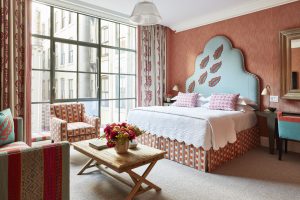 Luxurious junior suite at the Crosby Street Hotel, featuring vibrant decor, a cozy sitting area, and large windows.