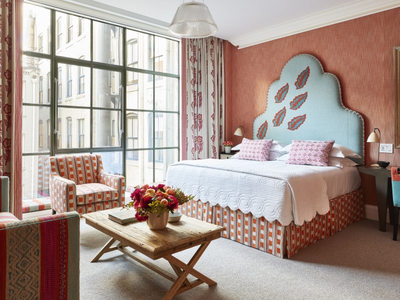 Luxurious junior suite at the Crosby Street Hotel, featuring vibrant decor, a cozy sitting area, and large windows.