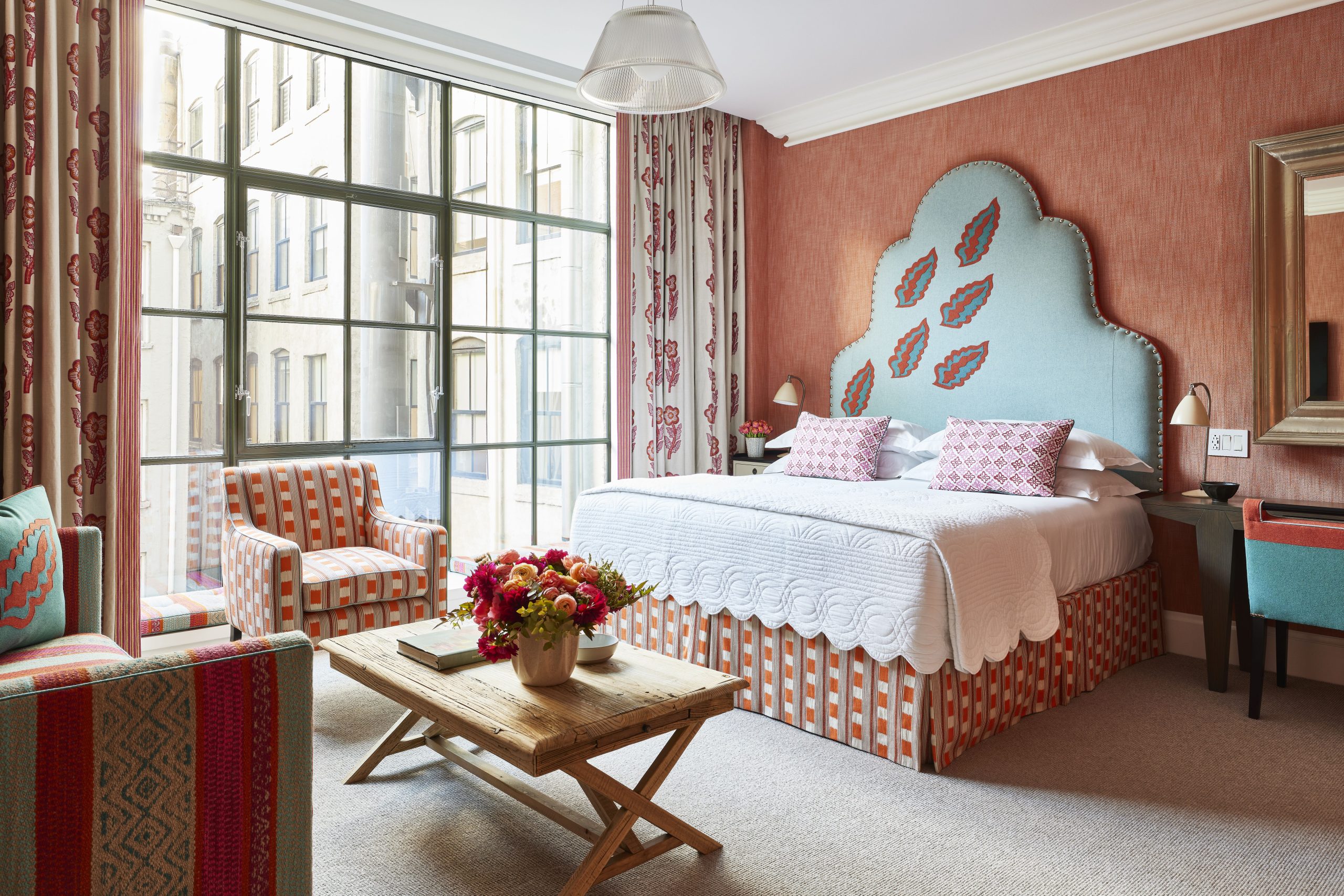 Luxurious junior suite at the Crosby Street Hotel, featuring vibrant decor, a cozy sitting area, and large windows.