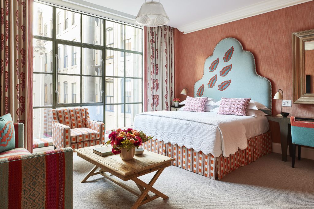 Luxury junior suite at Crosby Street Hotel featuring vibrant decor, a comfortable bed, and an inviting sitting area.