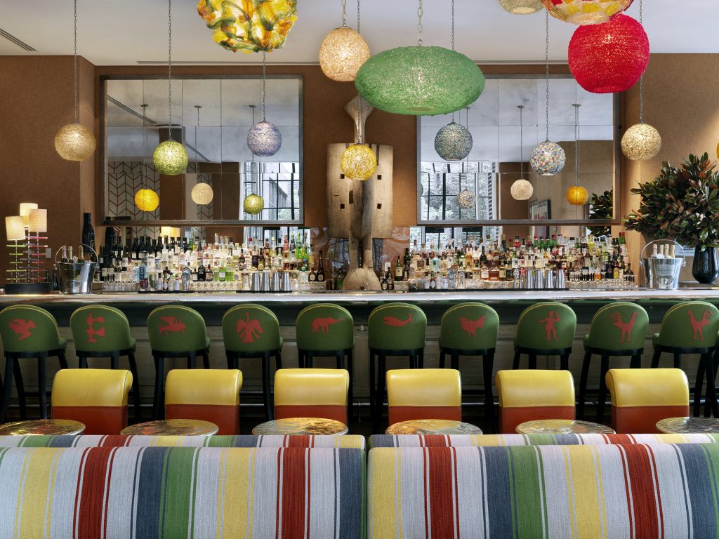 Stylish bar area at the Crosby Street Hotel featuring colorful seating and unique decorative lighting.