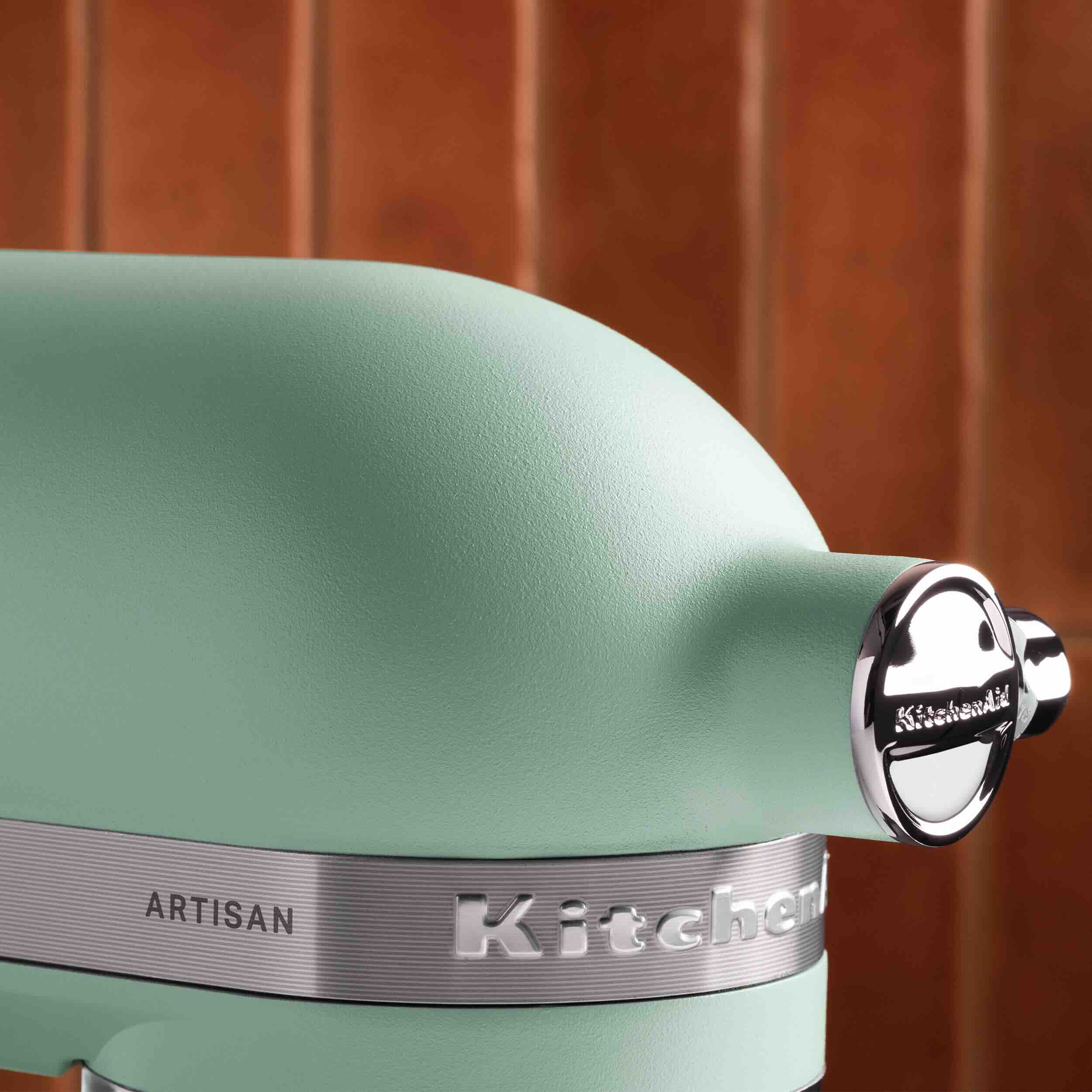 Close-up of a mint green KitchenAid mixer highlighting its sleek design and polished logo.