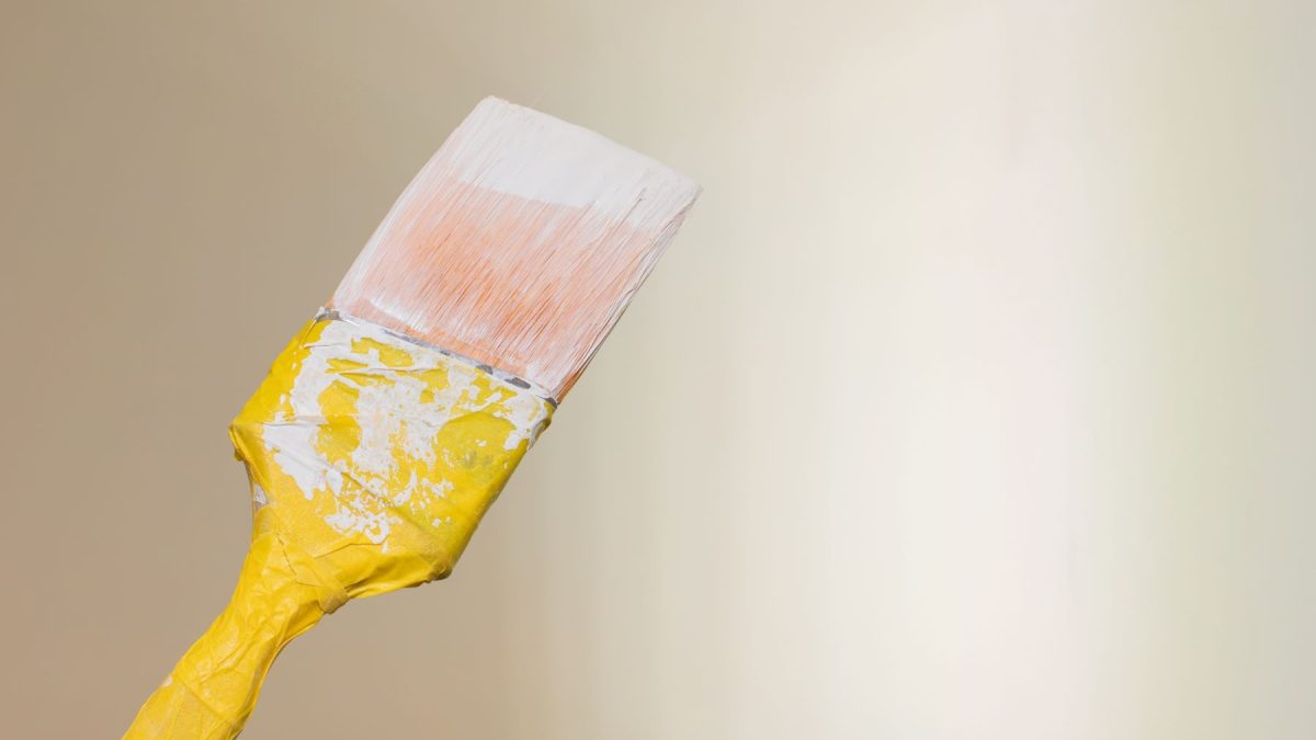 Paintbrush with yellow handle against a soft beige background, ideal for high-end home remodeling projects.