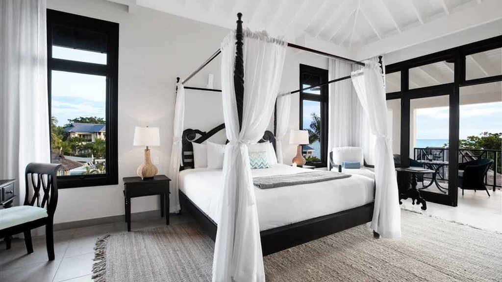 Luxurious bedroom with a four-poster bed, elegant decor, and large windows showcasing stunning views of the outdoors.