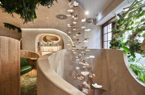 Interior of a holistic beauty space featuring hanging art pieces, lush greenery, and a modern, curved design aesthetic.