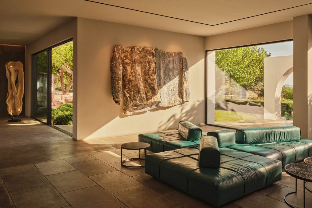 Stylish lounge area with modern furniture, artwork on the wall, and large windows showcasing a garden view.