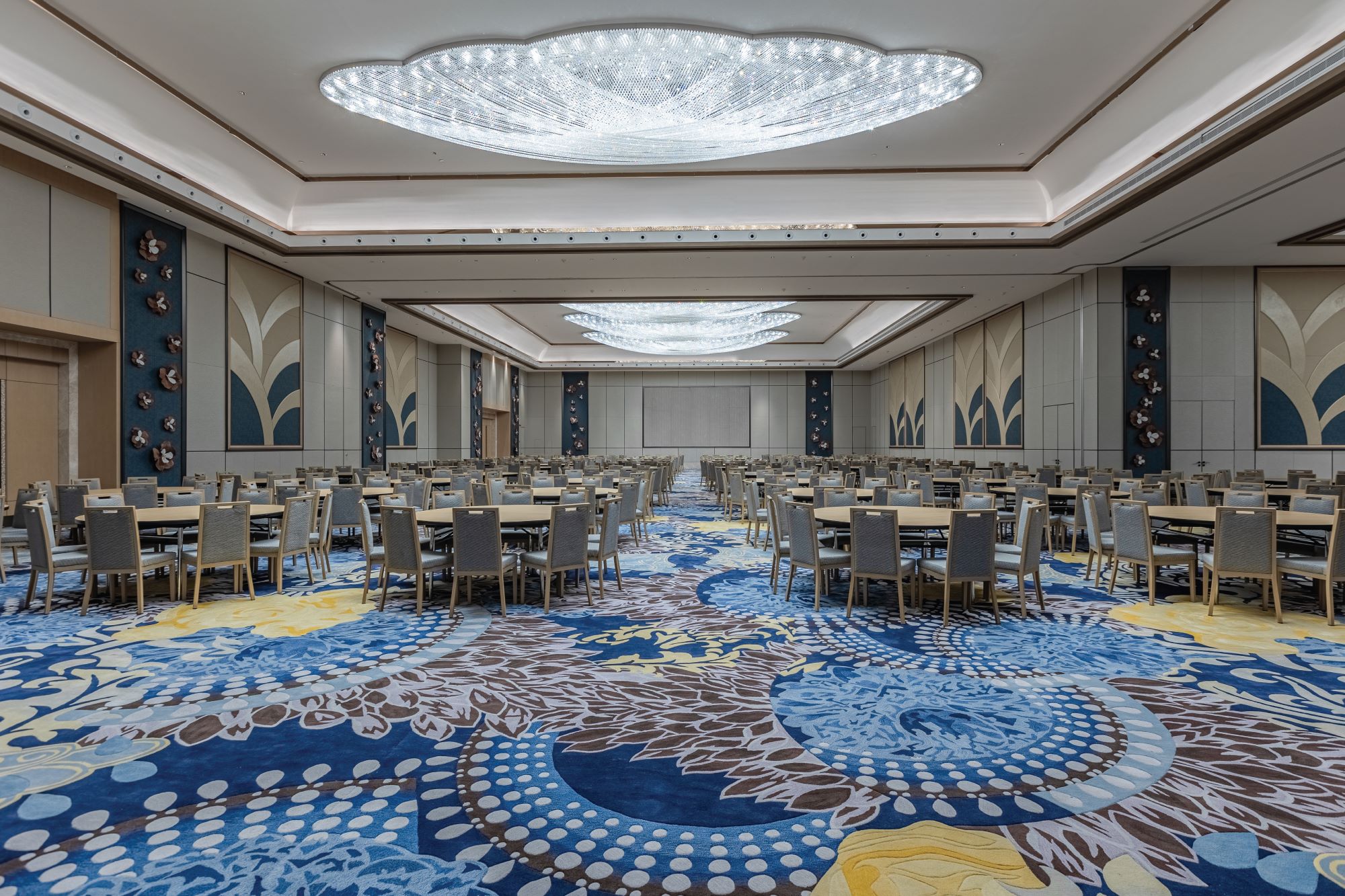 Luxurious event space featuring elegant chandeliers, modern decor, and a vibrant carpet design, ready for gatherings in Al-Rass.