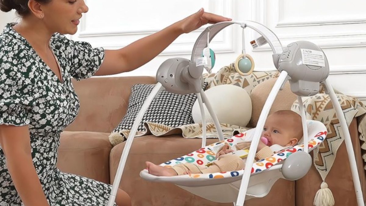A mother adjusts a baby swing while her baby sits comfortably, surrounded by a cozy living room setting.
