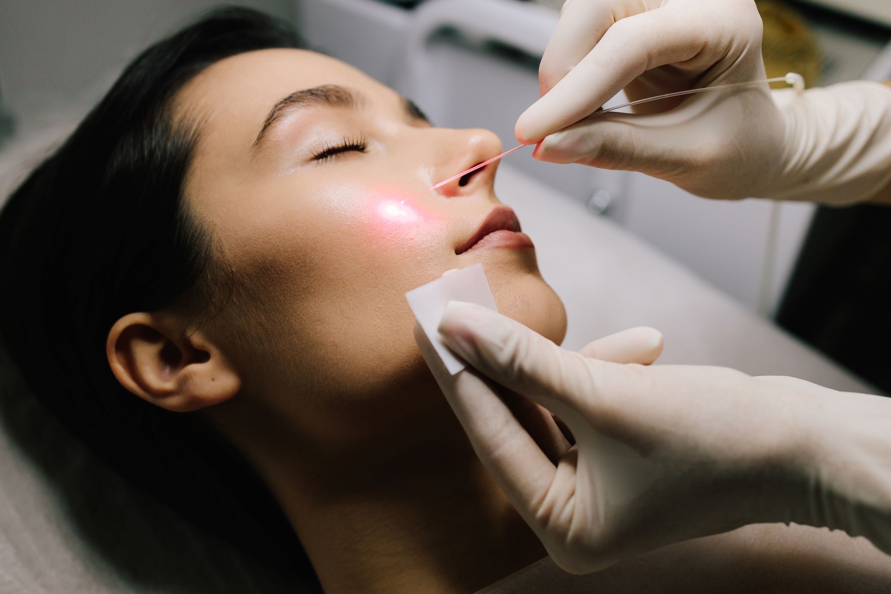 A healthcare professional applies a laser treatment to a patient's face during a facial rejuvenation procedure.