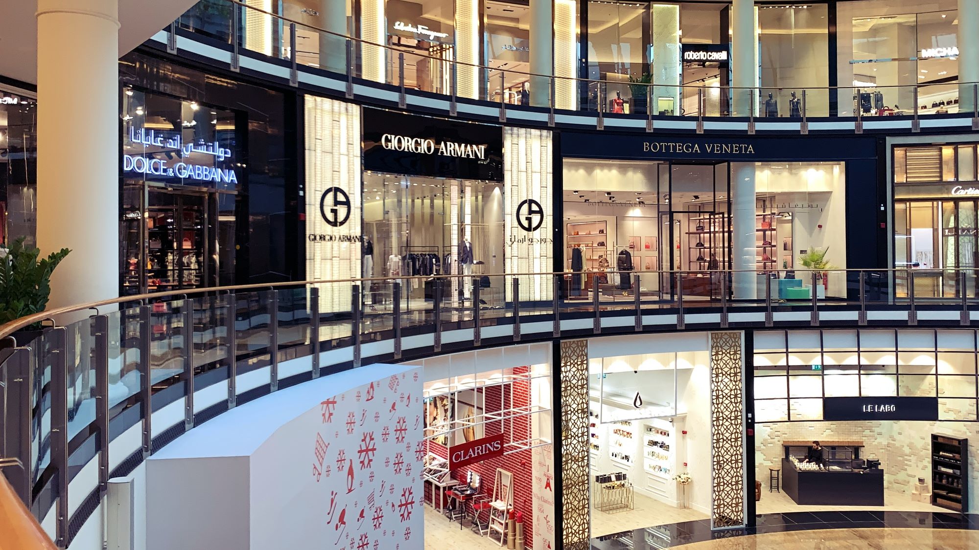 Luxury brand stores, including Giorgio Armani and Dolce & Gabbana, in a modern shopping mall interior.