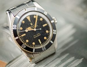 Vintage Rolex Submariner watch with a black dial and gold markers, showcasing its iconic design and aged patina.
