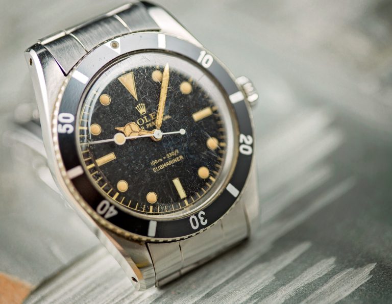 Vintage Rolex Submariner watch with a black dial and gold markers, showcasing its iconic design and aged patina.