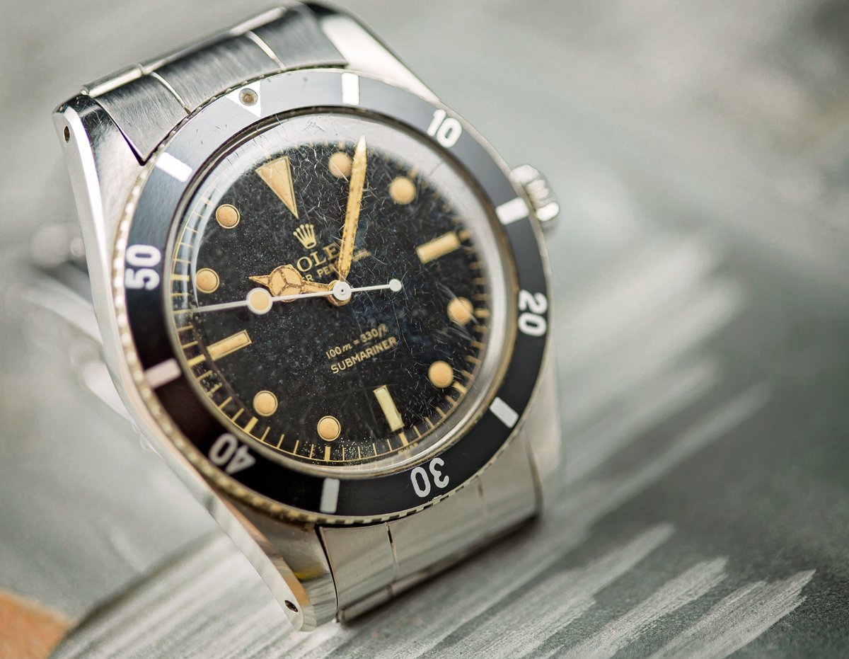 Vintage Rolex Submariner watch with a black dial and gold markers, showcasing its iconic design and aged patina.