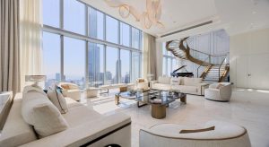 Luxurious penthouse living room with floor-to-ceiling windows, elegant furniture, and a stylish staircase leading to the upper floor.