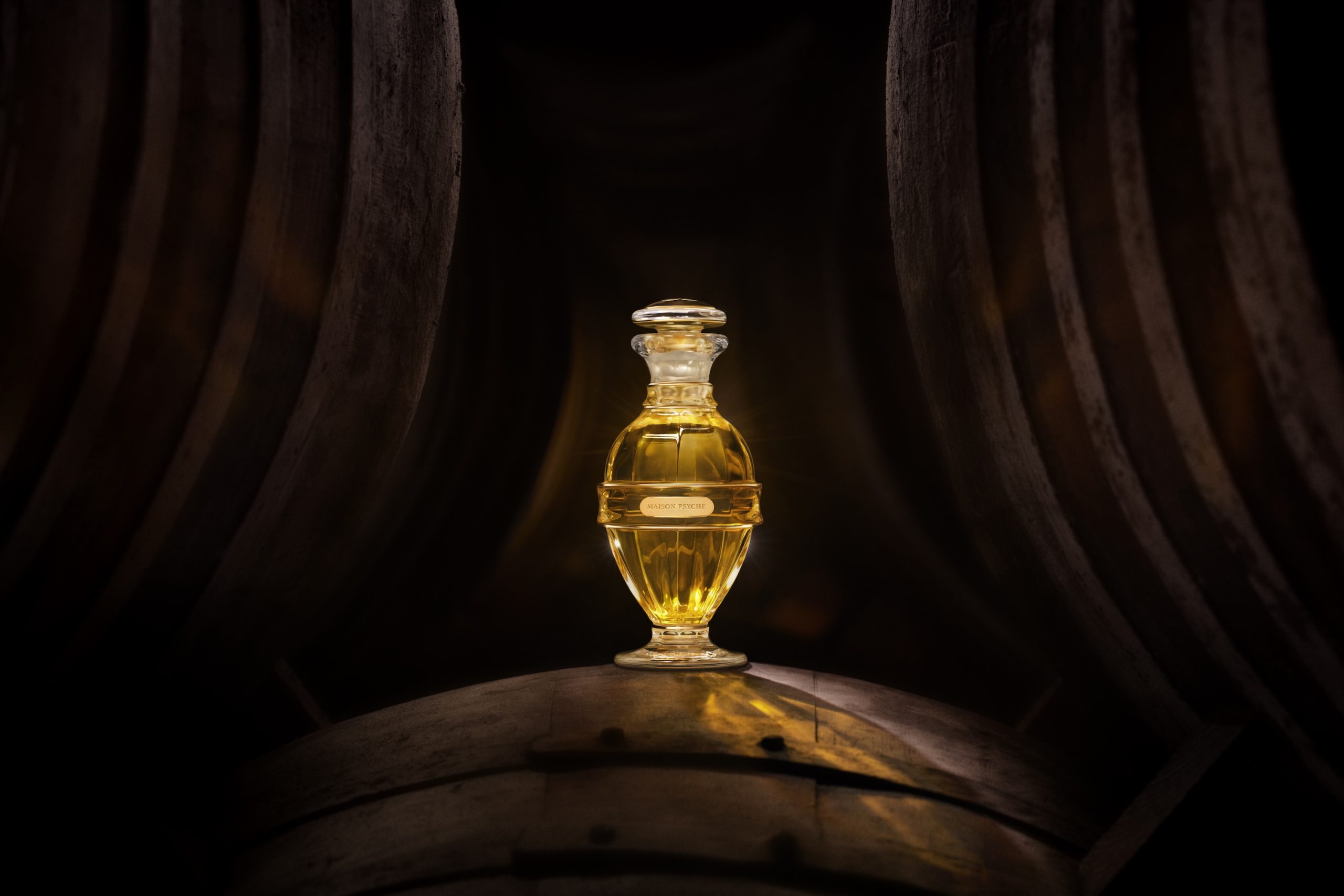 Elegant glass perfume bottle glowing amidst dark wooden barrels, representing the essence of Maison Psyché's luxurious fragrance.