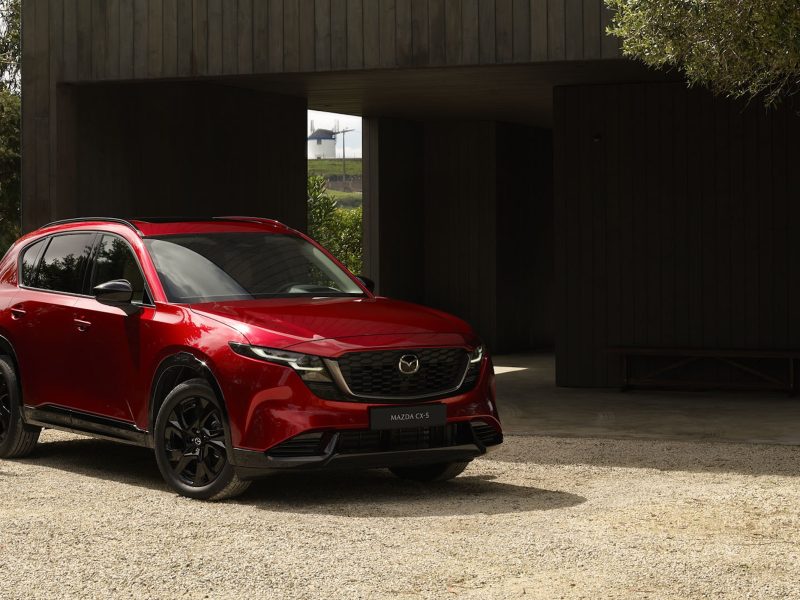 The 2026 Mazda CX-5 parked in a scenic area surrounded by greenery and modern architecture.