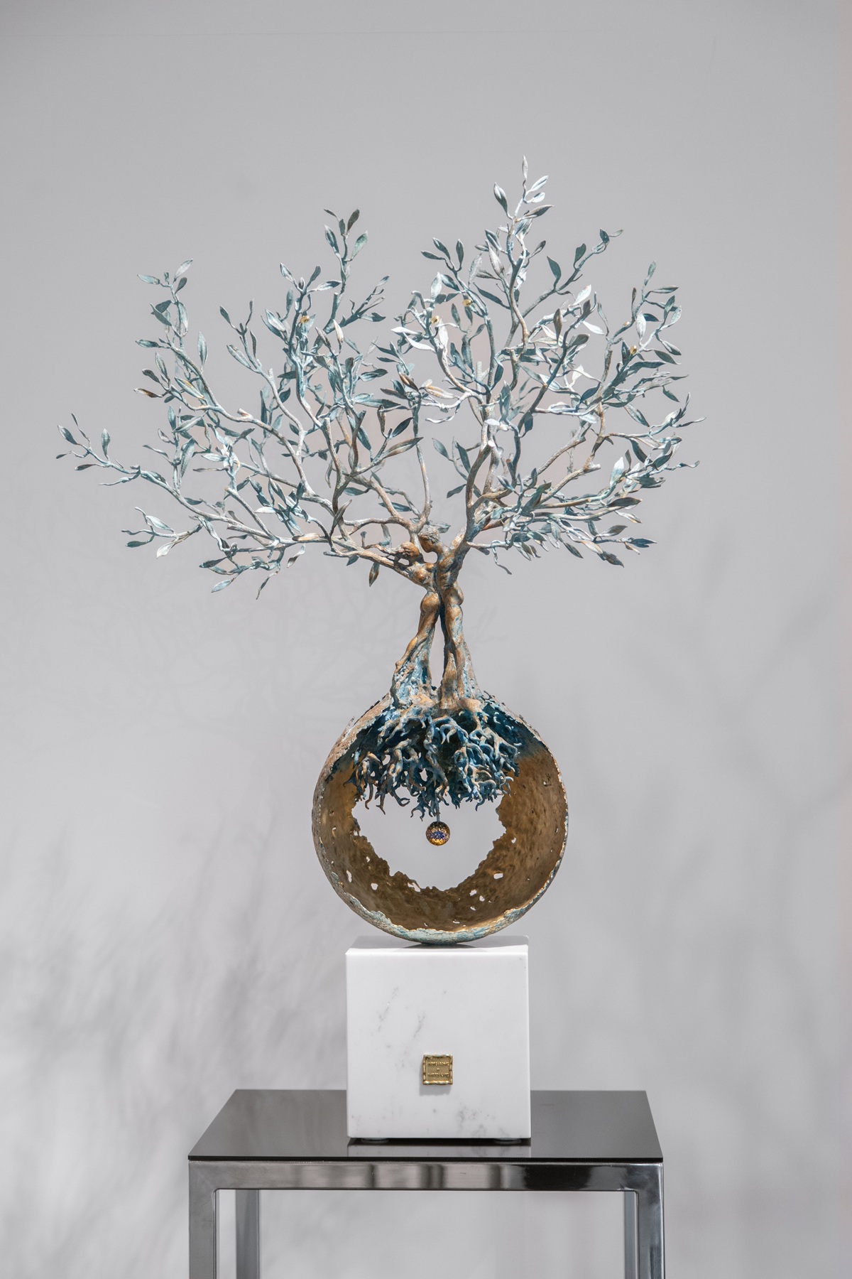 Sculpture titled "Energia della Vita," featuring a tree with a circular base and intricate branches, symbolizing life and harmony.