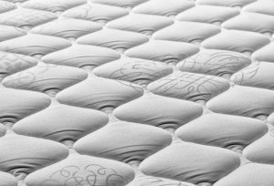 Close-up of a textured mattress surface, showcasing its tufted design for comfort and support.