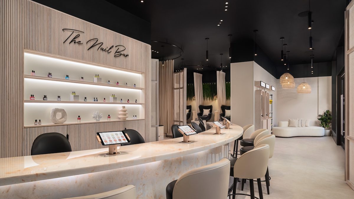 Modern nail bar interior featuring a sleek marble counter, a product display wall, and comfortable seating.