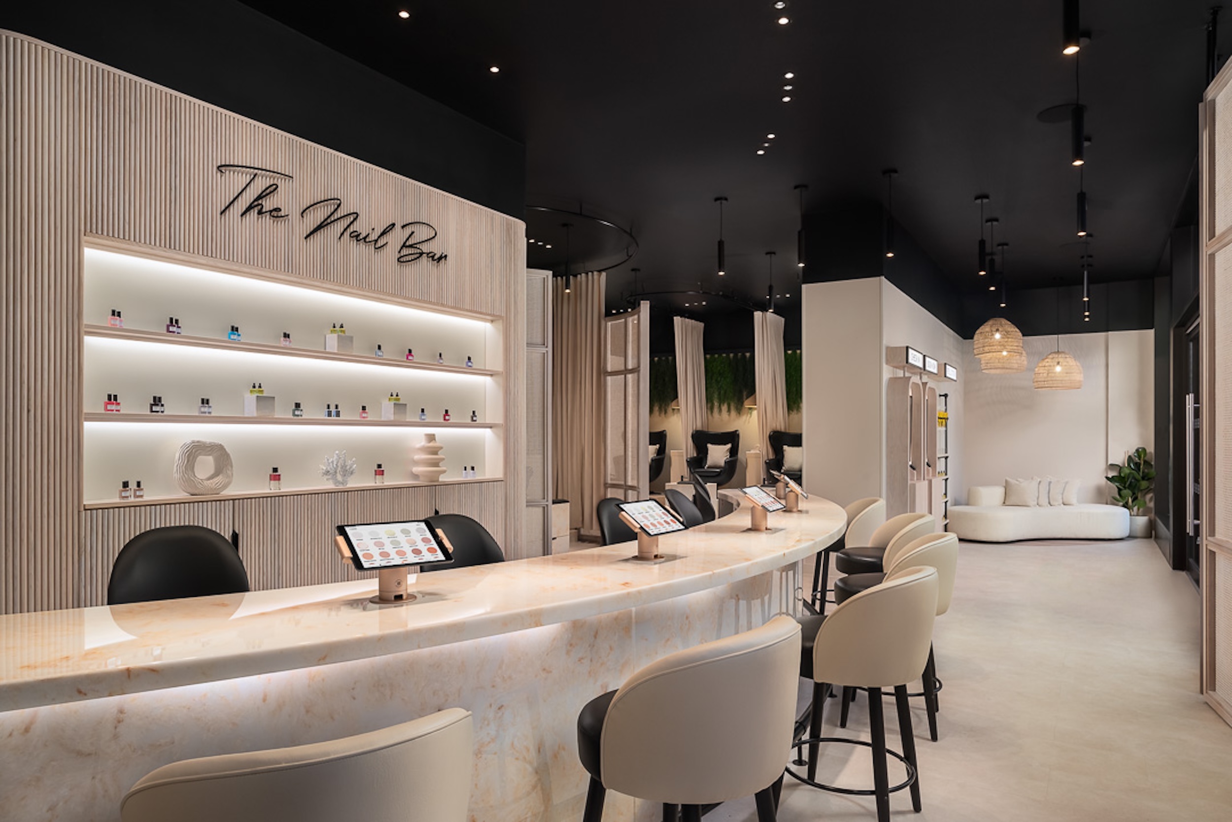 Modern nail bar interior featuring a sleek marble counter, a product display wall, and comfortable seating.