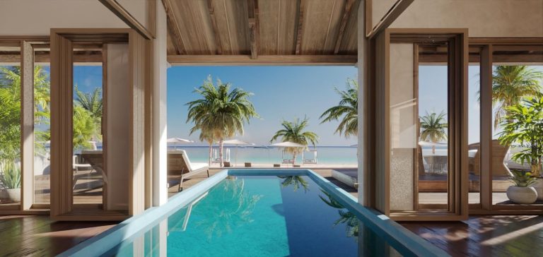 View of a serene pool area with tropical plants and umbrellas, leading to a tranquil beach and ocean in the background.