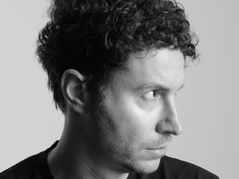 Profile portrait of Daniel Nadler, showcasing his curly hair and thoughtful expression against a light backdrop.