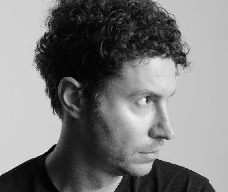 Profile portrait of Daniel Nadler, showcasing his curly hair and thoughtful expression against a light backdrop.