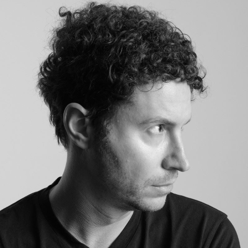 Profile portrait of Daniel Nadler, showcasing his curly hair and thoughtful expression against a light backdrop.
