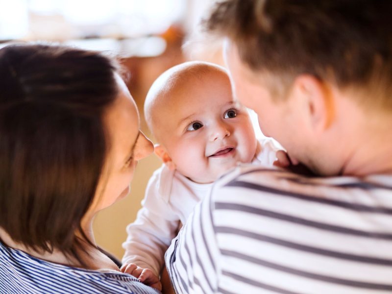 Smiling baby being held by parents, capturing a joyful moment in family life.
