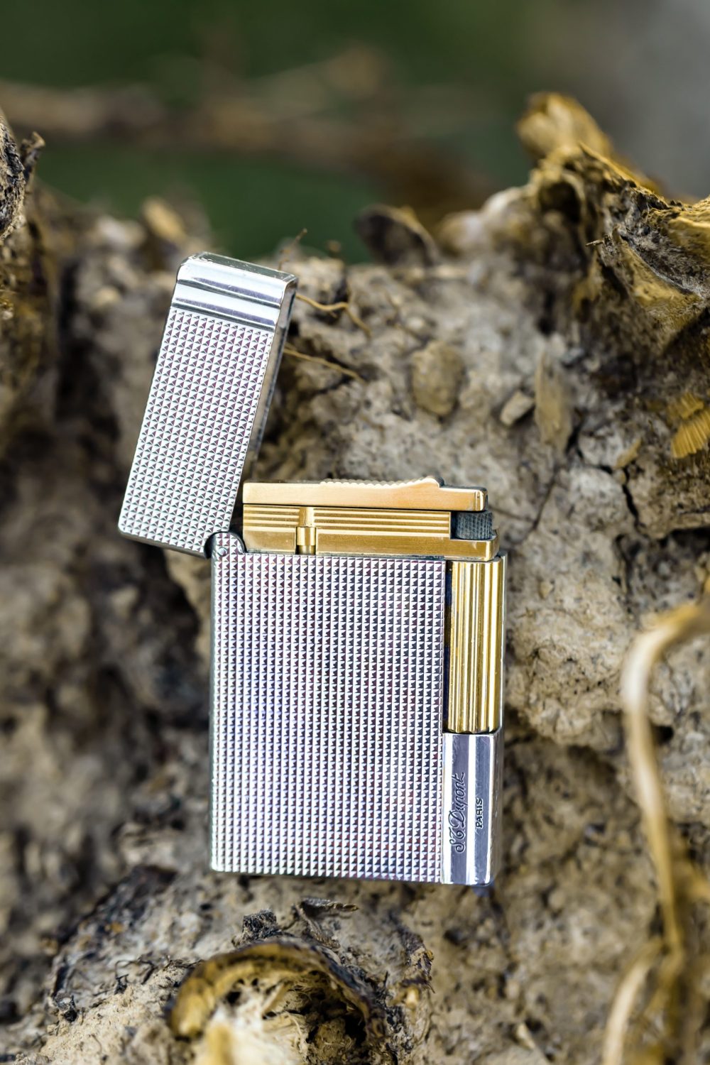 Luxury silver lighter with a gold accent against a rustic background, ideal for enhancing a cigar lounge experience.