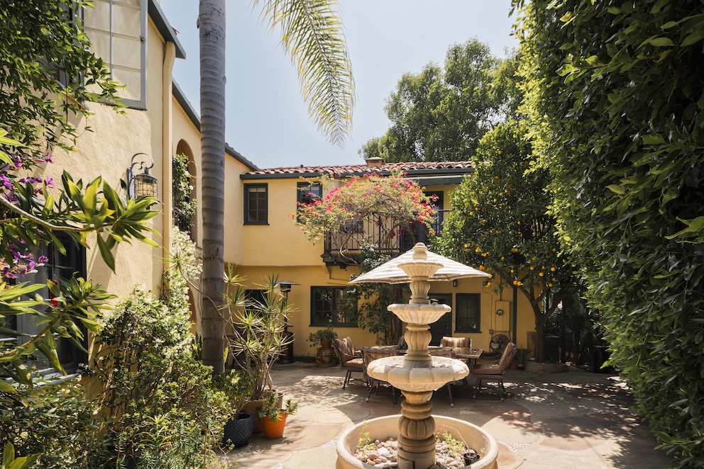 Charming courtyard of Casa Ivarene, featuring a fountain surrounded by lush greenery and colorful flowers in the Hollywood Hills.