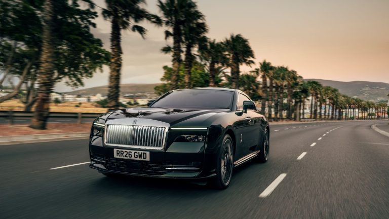 Rolls-Royce Spectre Series II driving on a palm-lined road at sunset, showcasing its luxury design and powerful presence.