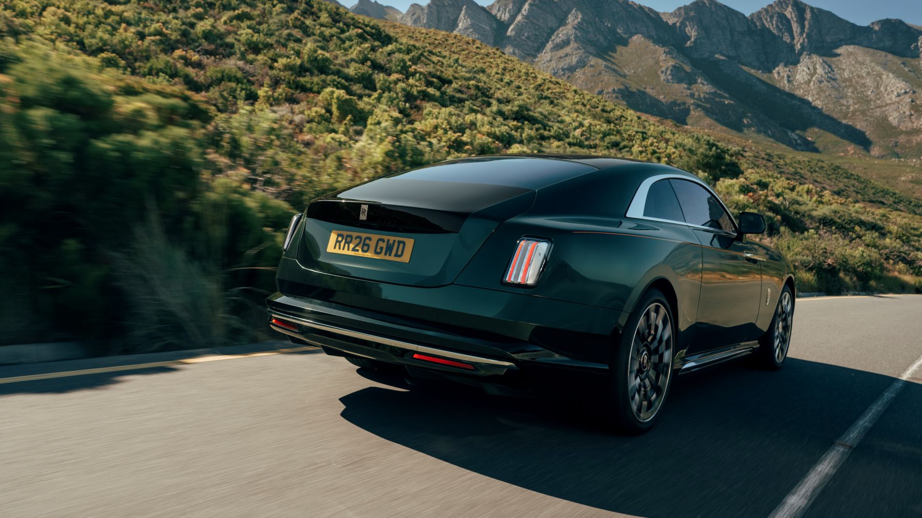 Rolls-Royce Spectre Series II driving along a scenic road, showcasing its elegant design and luxury features.
