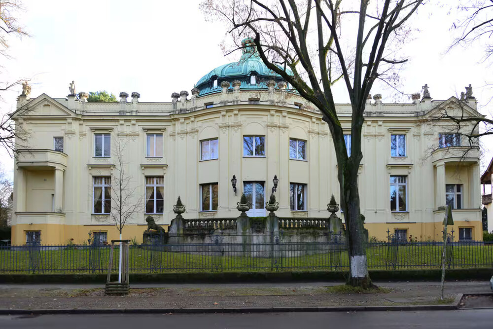 Historic building with a green dome surrounded by trees, located in the heart of Germany's Golden Triangle cities.