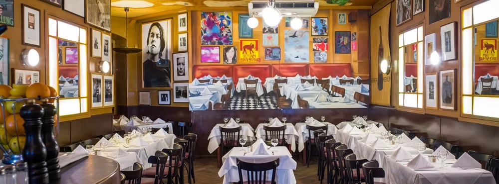 Elegant dining area featuring white tablecloths, framed artwork, and a warm ambiance in a Berlin restaurant.