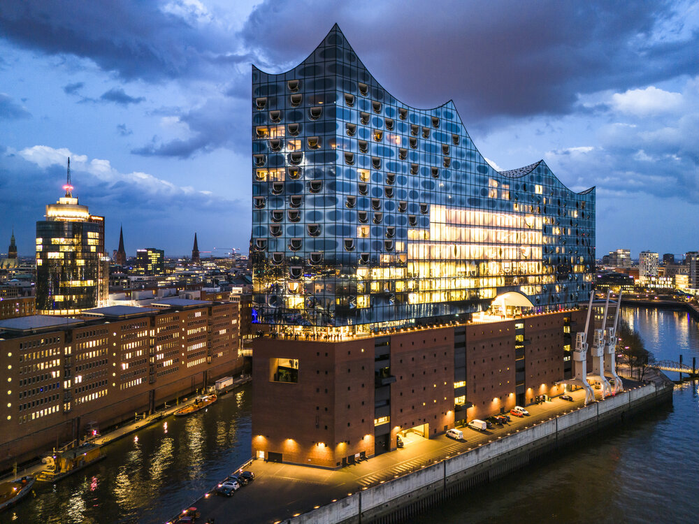 Aerial view of the Elbphilharmonie in Hamburg, showcasing its unique architecture illuminated at dusk.