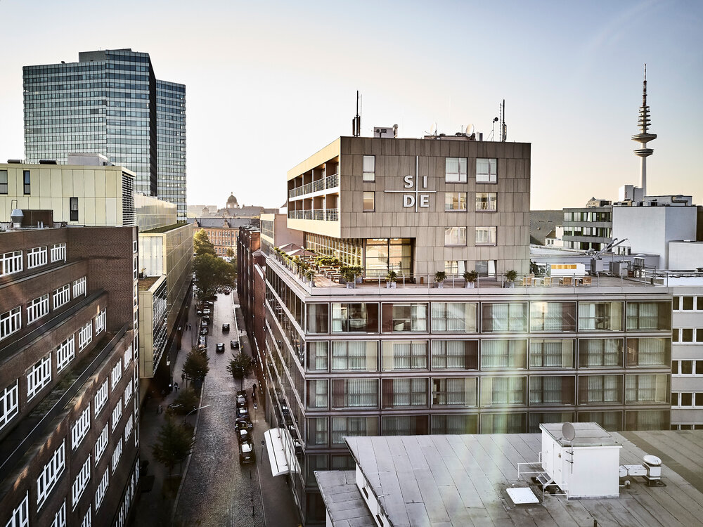 Modern buildings with a clear view of the street lined with trees, showcasing architectural styles in a cityscape.